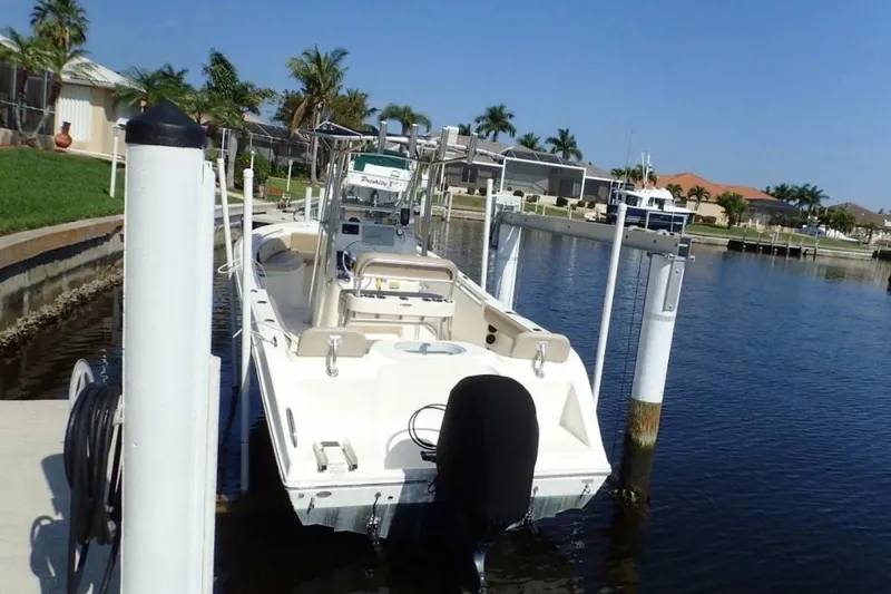Slide: The Image of 2023 Cobia 217 CC boat docked in a sunny waterfront setting. - 5