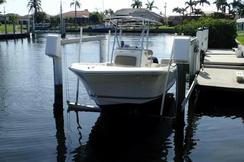 Slide: The Image of 2023 Cobia 217 CC boat docked on a lift in a scenic marina. - 8