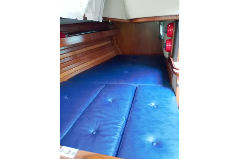 Slide: The Image of 1982 C&C Landfall 35 interior with blue cushioned berth and wooden paneling. - 11