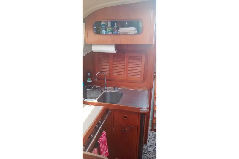 Slide: The Image of 1982 C&C Landfall 35 yacht interior kitchen with wooden cabinets and dual sink. - 7