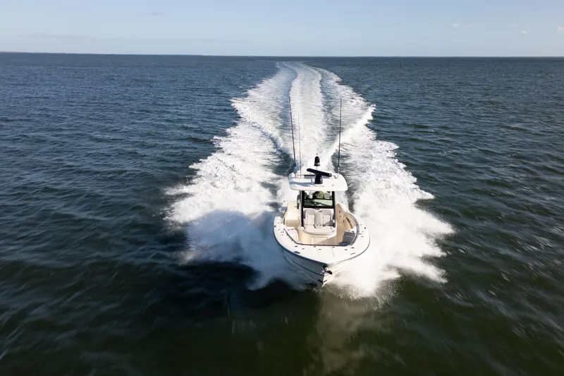 Slide: The Image of 2024 Scout 330 LXF boat cruising on open water, leaving a wake trail. - 12