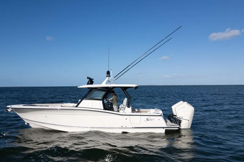 Slide: The Image of 2024 Scout 330 LXF boat cruising on open water under clear blue sky. - 18