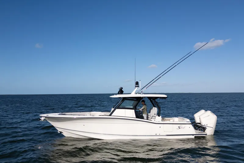 Slide: The Image of 2024 Scout 330 LXF boat cruising on open water under clear blue sky. - 19