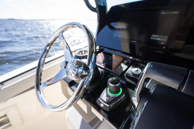 Slide: The Image of Steering wheel and controls of 2024 Scout 330 LXF boat on open water. - 20