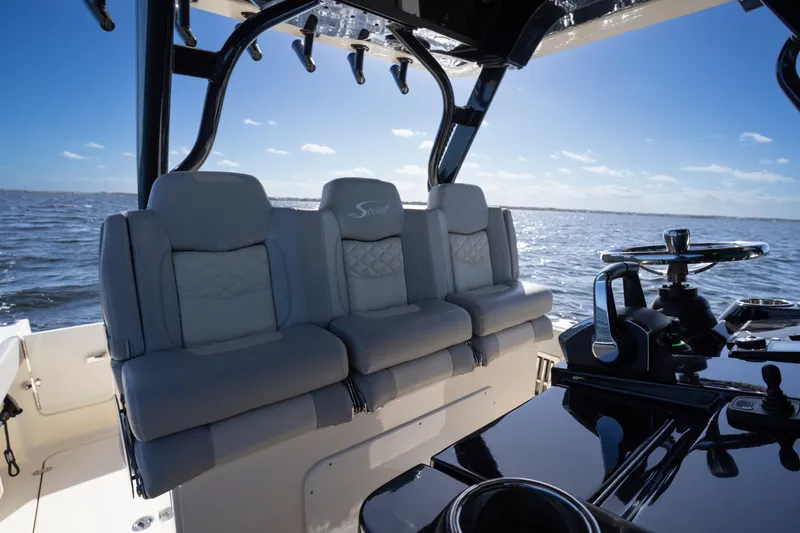 Slide: The Image of 2024 Scout 330 LXF boat interior with luxurious seating and steering console on open water. - 21