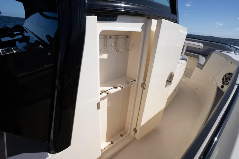 Slide: The Image of 2024 Scout 330 LXF boat interior with open storage compartment and hooks. - 33