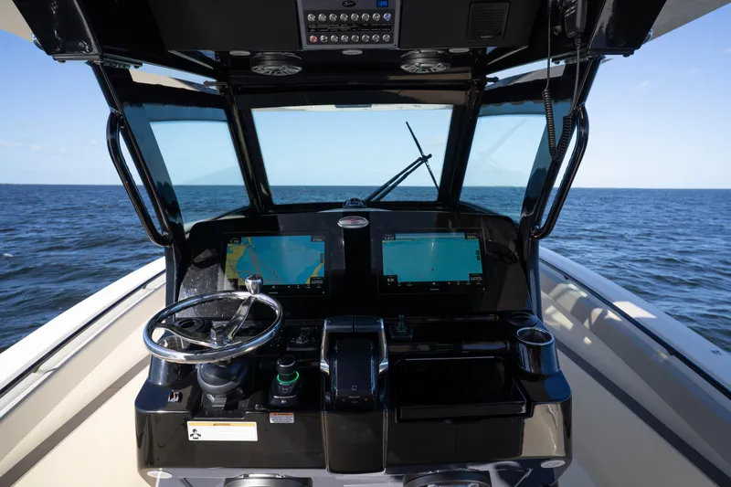 Slide: The Image of 2024 Scout 330 LXF boat helm with dual navigation screens on open water. - 47