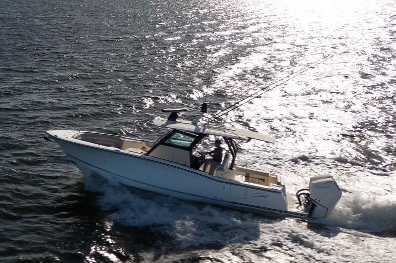 Slide: The Image of 2024 Scout 330 LXF boat cruising on open water, sun reflecting on waves. - 5