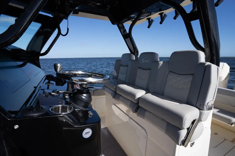 Slide: The Image of 2024 Scout 330 LXF boat interior with luxurious seating and steering wheel, on open water. - 50