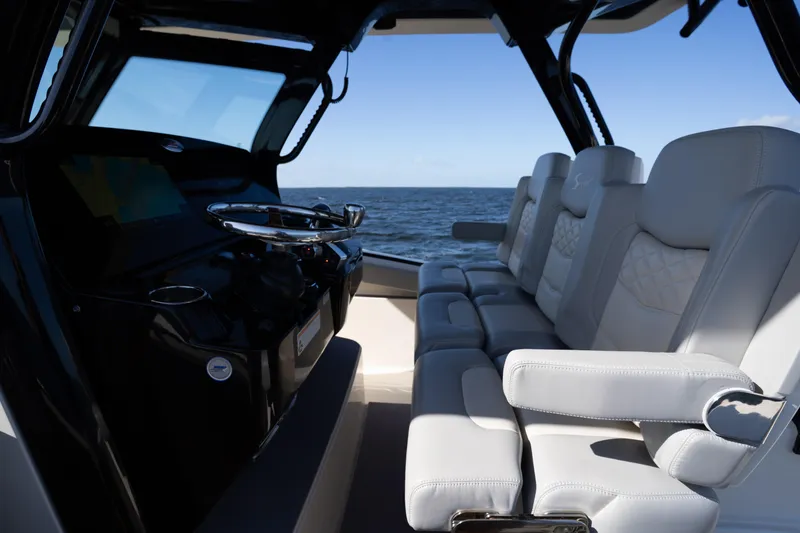 Slide: The Image of 2024 Scout 330 LXF boat interior with luxurious seating and steering console, ocean view. - 51