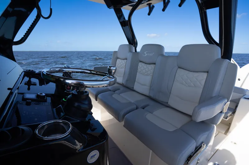 Slide: The Image of 2024 Scout 330 LXF boat interior with luxurious seating and steering wheel, ocean view. - 52