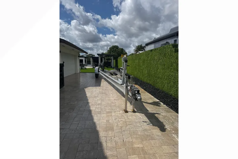 Slide: The Image of 2024 Scout 330 LXF boat trailer parked on a paved driveway under a cloudy sky. - 65