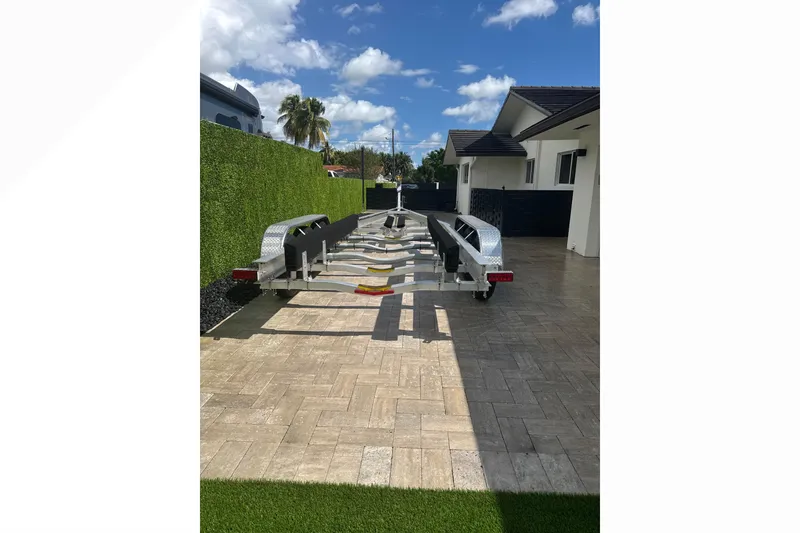 Slide: The Image of 2024 Scout 330 LXF boat trailer parked on paved driveway under blue sky. - 66