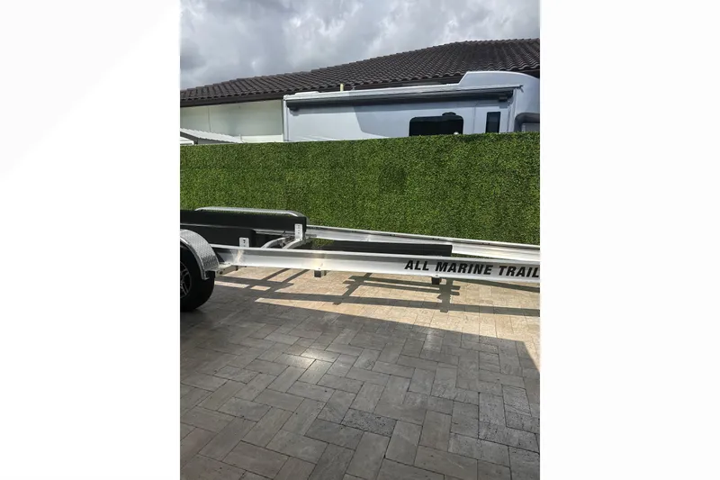 Slide: The Image of Trailer for 2024 Scout 330 LXF boat parked on paved driveway. - 67