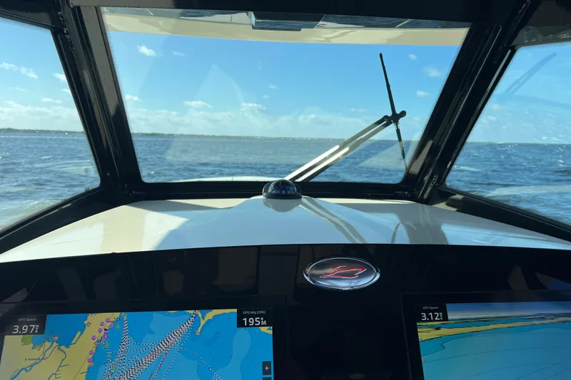 Slide: The Image of 2024 Scout 330 LXF boat dashboard with navigation screens, ocean view through windshield. - 78