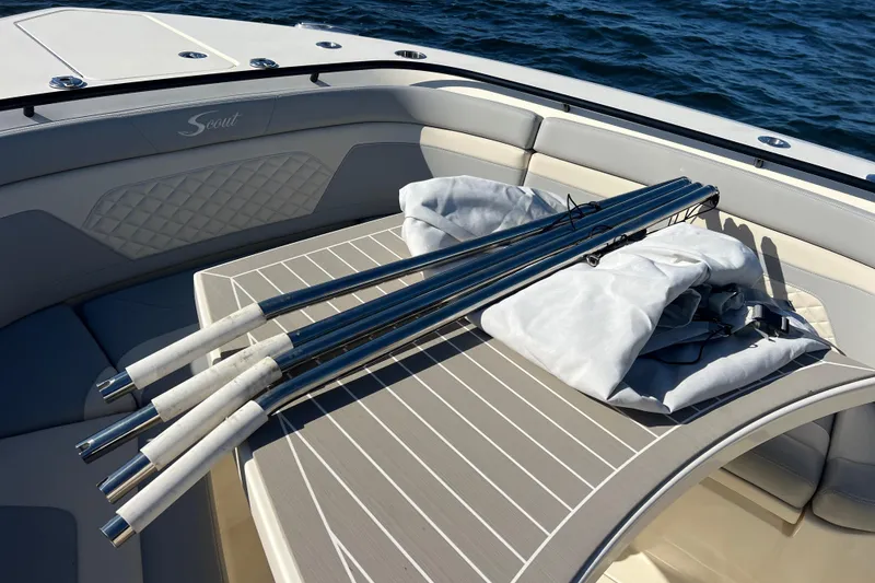 Slide: The Image of 2024 Scout 330 LXF boat interior with fishing rods on deck, ocean background. - 80