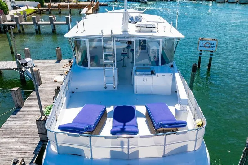 Slide: The Image of 2003 Hatteras 75' Cockpit MY yacht docked, featuring sun loungers and a spacious deck. - 24