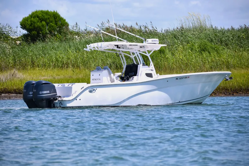 Slide: The Image of 2020 Sea Fox 288 Commander boat on water with Yamaha engines, near grassy shoreline. - 4