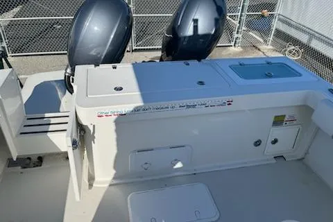 Slide: The Image of 2020 Parker 2501 Center Console boat with dual outboard engines, docked near a chain-link fence. - 4