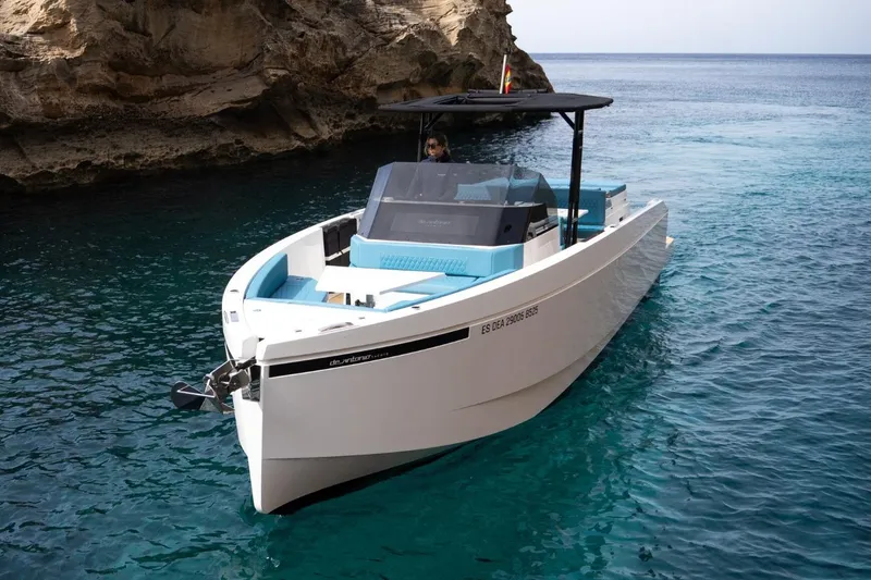 Slide: The Image of 2026 De Antonio Yachts D29 in clear blue waters near rocky cliffs. - 12