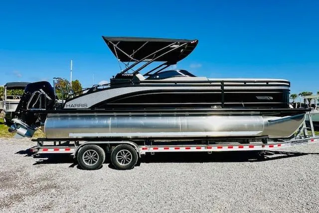 The Image of 2026 Harris Solstice DC 250 pontoon boat on a trailer, under clear blue sky. - 0