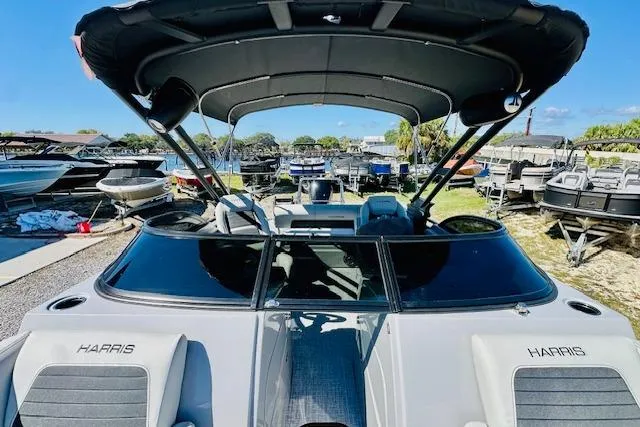 Slide: The Image of 2026 Harris Solstice DC 250 boat with canopy, docked among other boats. - 11