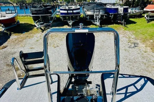 Slide: The Image of 2026 Harris Solstice DC 250 boat, rear view with motor, docked among other boats. - 22