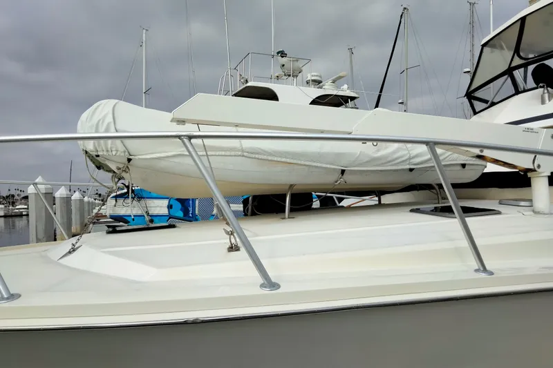 Slide: The Image of 1988 Viking 48 Convertible yacht with covered dinghy on deck, docked at marina. - 3