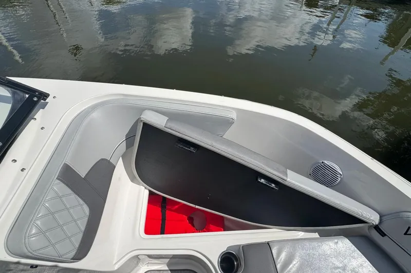 Slide: The Image of 2023 Bayliner VR6 Bowrider OB interior with open storage compartment and water reflection. - 13