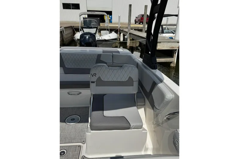 Slide: The Image of 2023 Bayliner VR6 Bowrider OB interior with gray seating at a marina. - 18