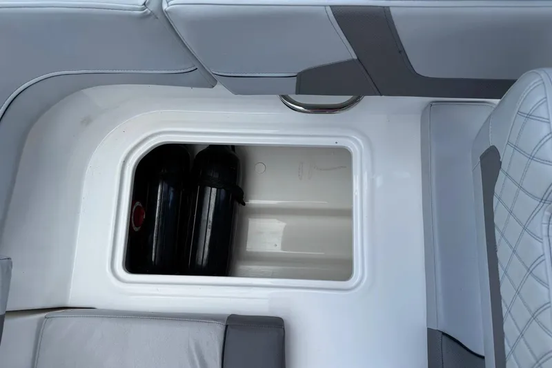 Slide: The Image of 2023 Bayliner VR6 Bowrider OB storage compartment with two black canisters. - 27