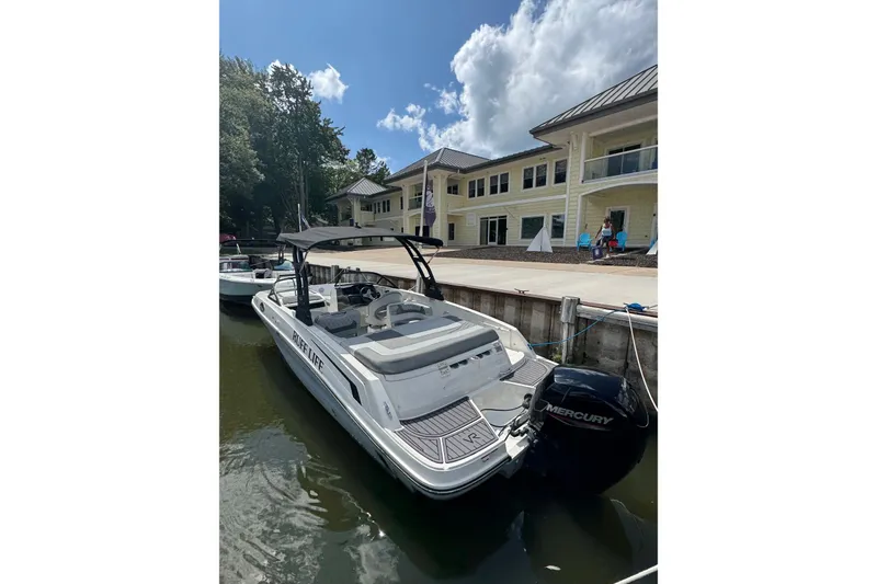 Slide: The Image of 2023 Bayliner VR6 Bowrider OB docked near a waterfront building under a blue sky. - 4
