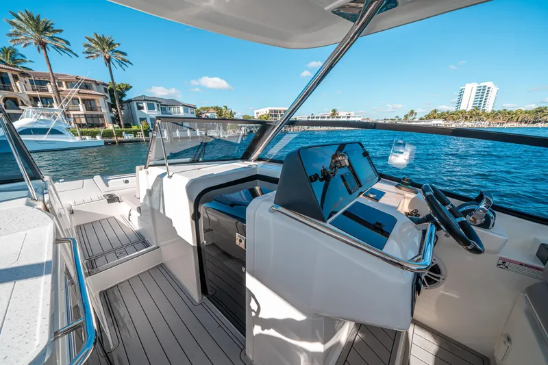 Slide: The Image of 2022 Aquila 32 Sport boat interior with modern helm, docked near waterfront homes. - 26