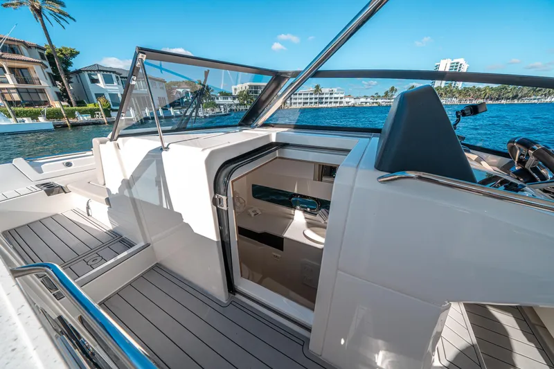 Slide: The Image of 2022 Aquila 32 Sport yacht interior with open cabin door, docked by waterfront homes. - 27