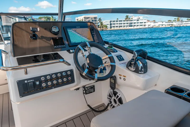 Slide: The Image of Helm of 2022 Aquila 32 Sport boat with navigation controls and ocean view. - 39