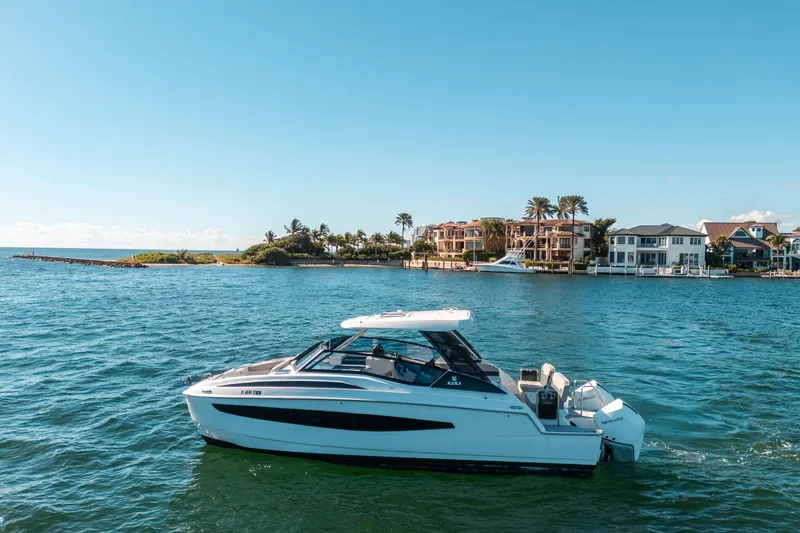 Slide: The Image of 2022 Aquila 32 Sport boat cruising near luxury waterfront homes. - 50