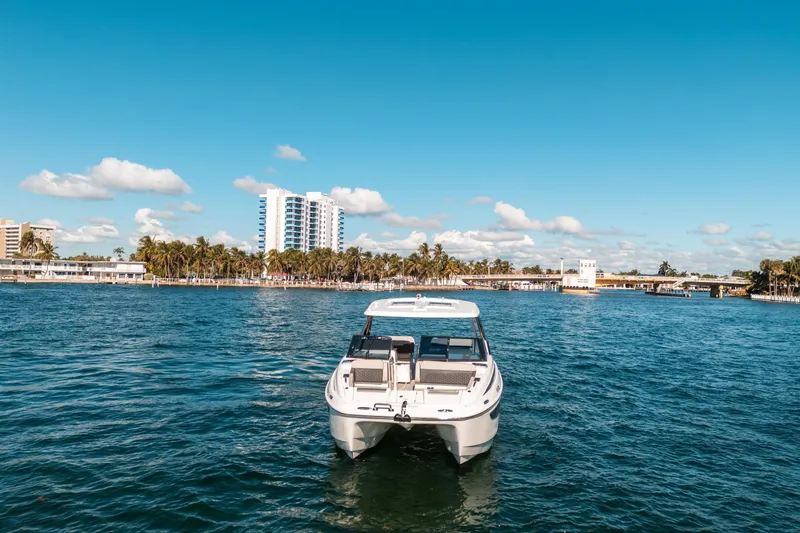 Slide: The Image of Aquila 32 Sport 2022 boat on water with cityscape and palm trees in background. - 53