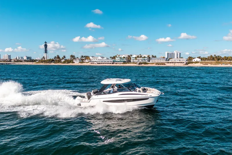 Slide: The Image of Aquila 32 Sport 2022 cruising near a coastal city with a lighthouse in the background. - 57