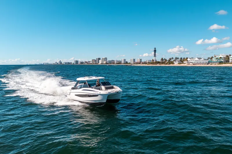 Slide: The Image of Aquila 32 Sport 2022 cruising on ocean near city skyline and lighthouse. - 58