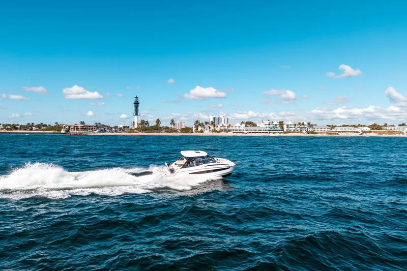 Slide: The Image of Aquila 32 Sport 2022 cruising on blue ocean near coastal cityscape. - 60