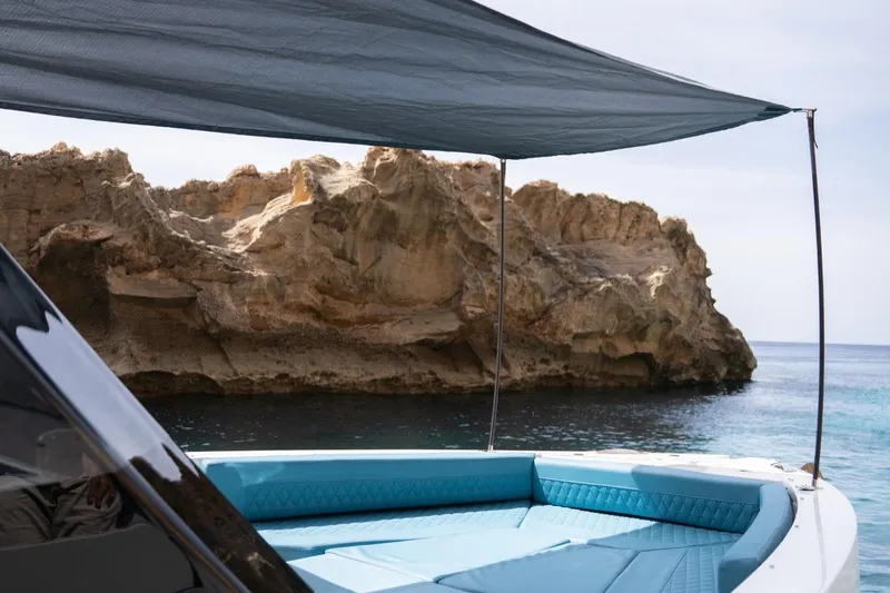 Slide: The Image of 2026 De Antonio Yachts D29 with sunshade, near rocky coastline. - 24