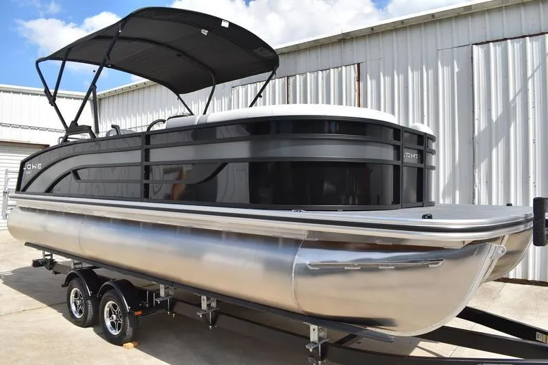 Slide: The Image of 2023 Lowe SS 230 DV pontoon boat with canopy, parked on trailer. - 2