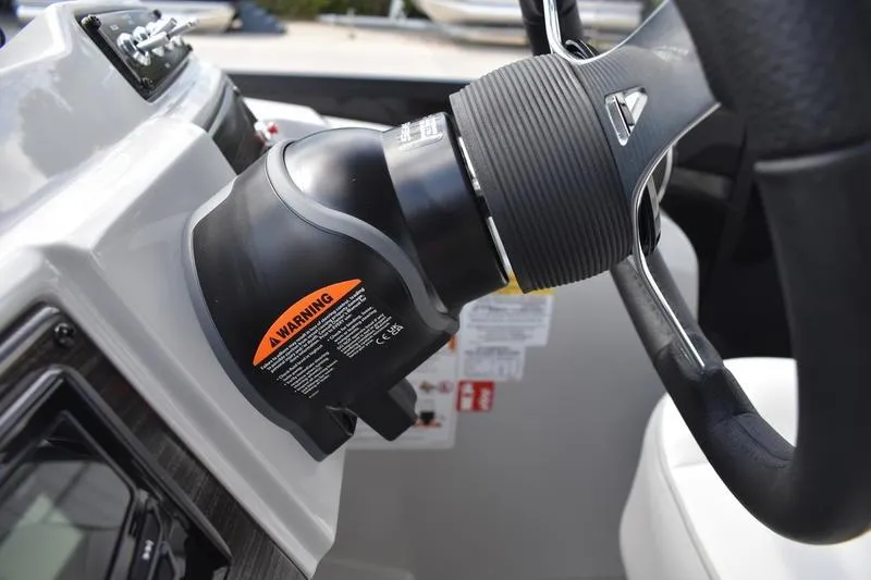 Slide: The Image of Steering wheel and controls of 2023 Lowe SS 230 DV boat, featuring warning label. - 28