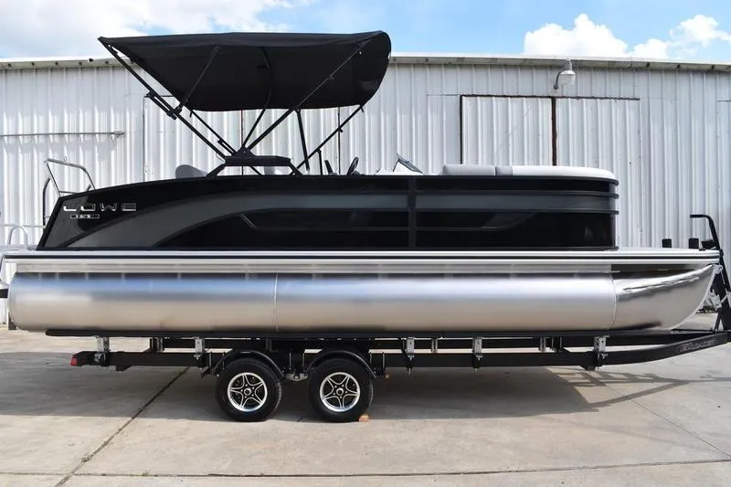 The Image of 2023 Lowe SS 230 DV pontoon boat with canopy on trailer, parked outdoors. - 0
