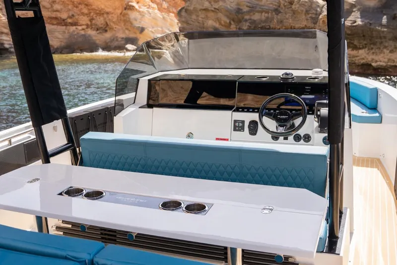 Slide: The Image of 2026 De Antonio Yachts D29 interior with modern helm and seating, docked by rocky shore. - 21