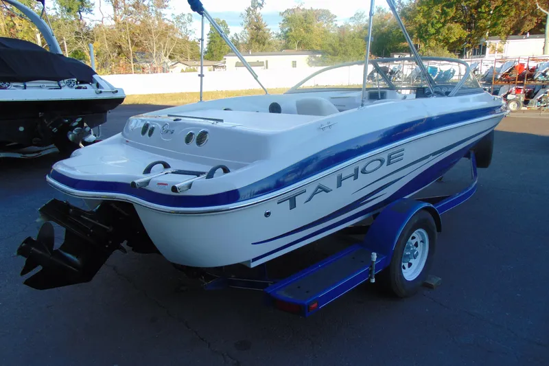 Slide: The Image of 2007 Tahoe Q4 I/O Sport boat on trailer, white and blue design, parked outdoors. - 3