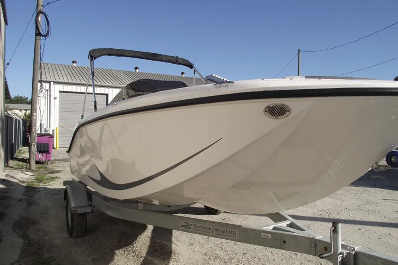 Slide: The Image of 2026 Bayliner M19 boat on trailer, parked outdoors under clear blue sky. - 2