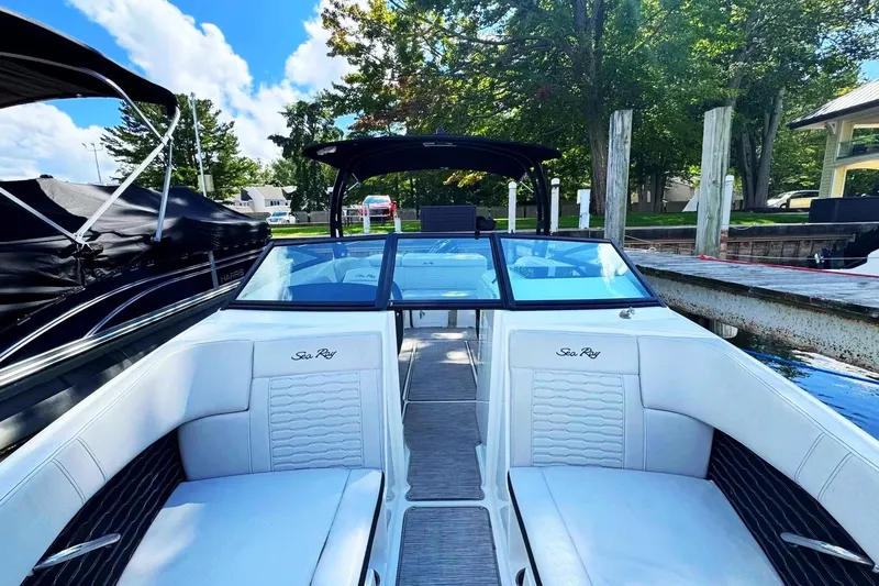 Slide: The Image of 2021 Sea Ray SPX 230 Outboard boat with white seating, docked by a scenic waterfront. - 13