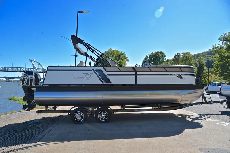 Slide: The Image of 2023 Viaggio Lago 22 R pontoon boat on trailer by riverside under clear blue sky. - 15