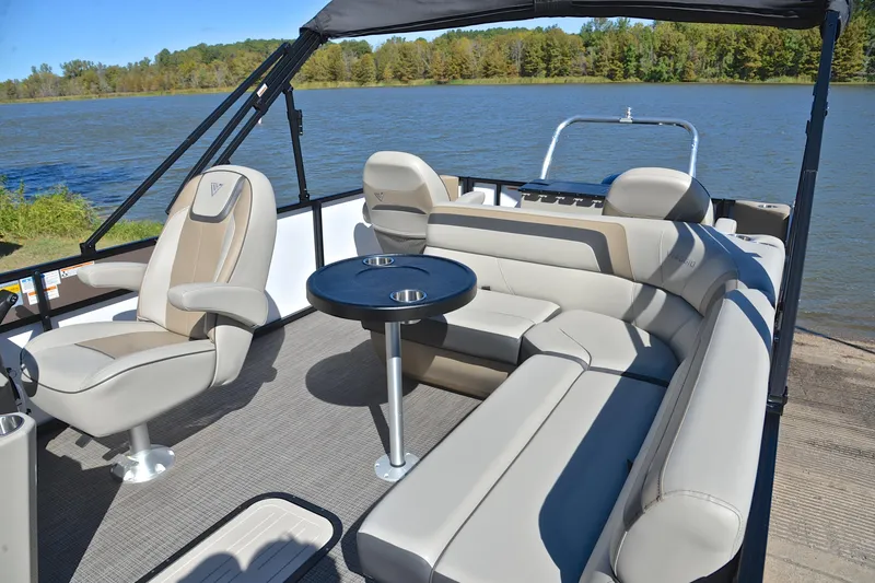 Slide: The Image of 2023 Viaggio Lago 22 R pontoon boat interior with plush seating and table on a lake. - 23